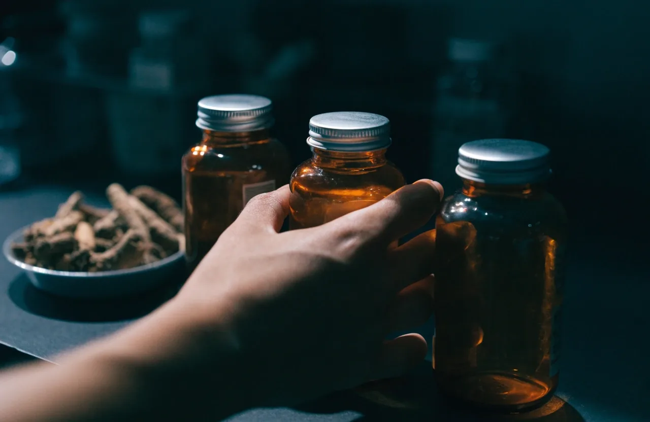 Three unlabelled amber bottles lined up on a matte shelf at night, seen in profile
